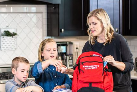 Mom and 2 kids packing emergency supplies in backpack